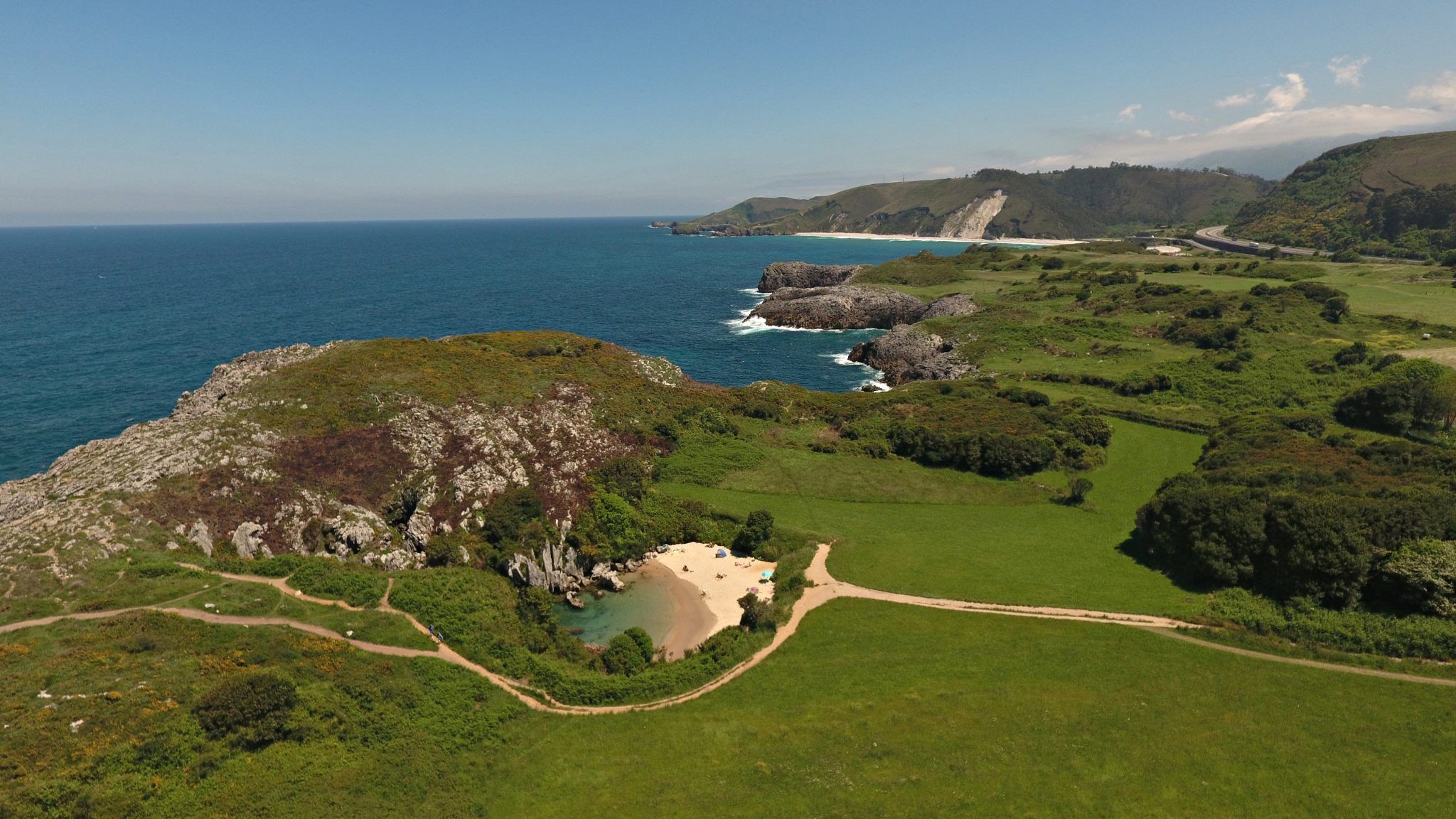 alt=" Vista de la Playa de Gulpiyuri en Llanes, Asturias, pequeña playa interior rodeada de praderas, inicio de la Ruta Senderista "