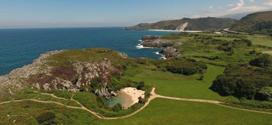 alt=" Vista de la Playa de Gulpiyuri en Llanes, Asturias, pequeña playa interior rodeada de praderas, inicio de la Ruta Senderista "
