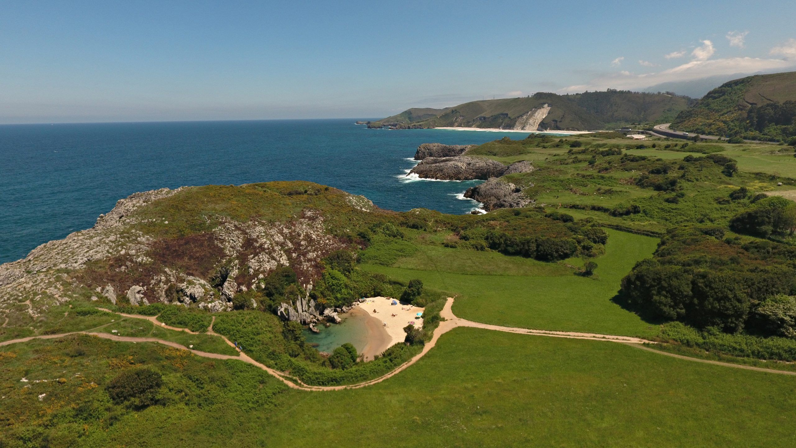alt=" Vista de la Playa de Gulpiyuri en Llanes, Asturias, pequeña playa interior rodeada de praderas, inicio de la Ruta Senderista "