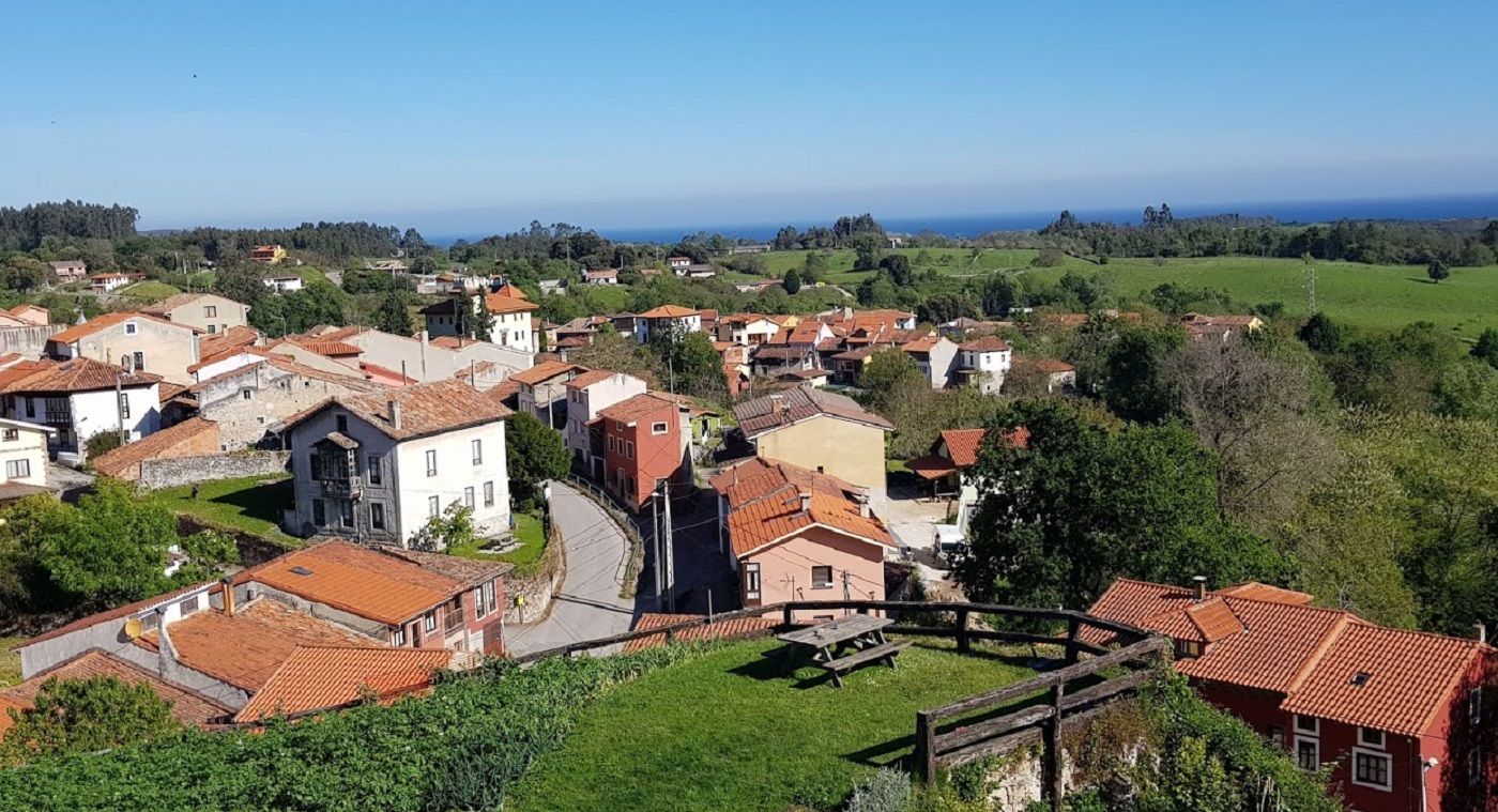 alt="Vista de Porrúa, un encantador pueblo en Llanes, Asturias, conocido por su arquitectura tradicional, paisajes verdes y ambiente rural."