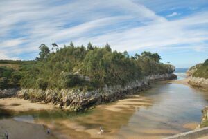 alt="Playa de Guadamía con marea baja, mostrando su aspecto de laguna fluvial.