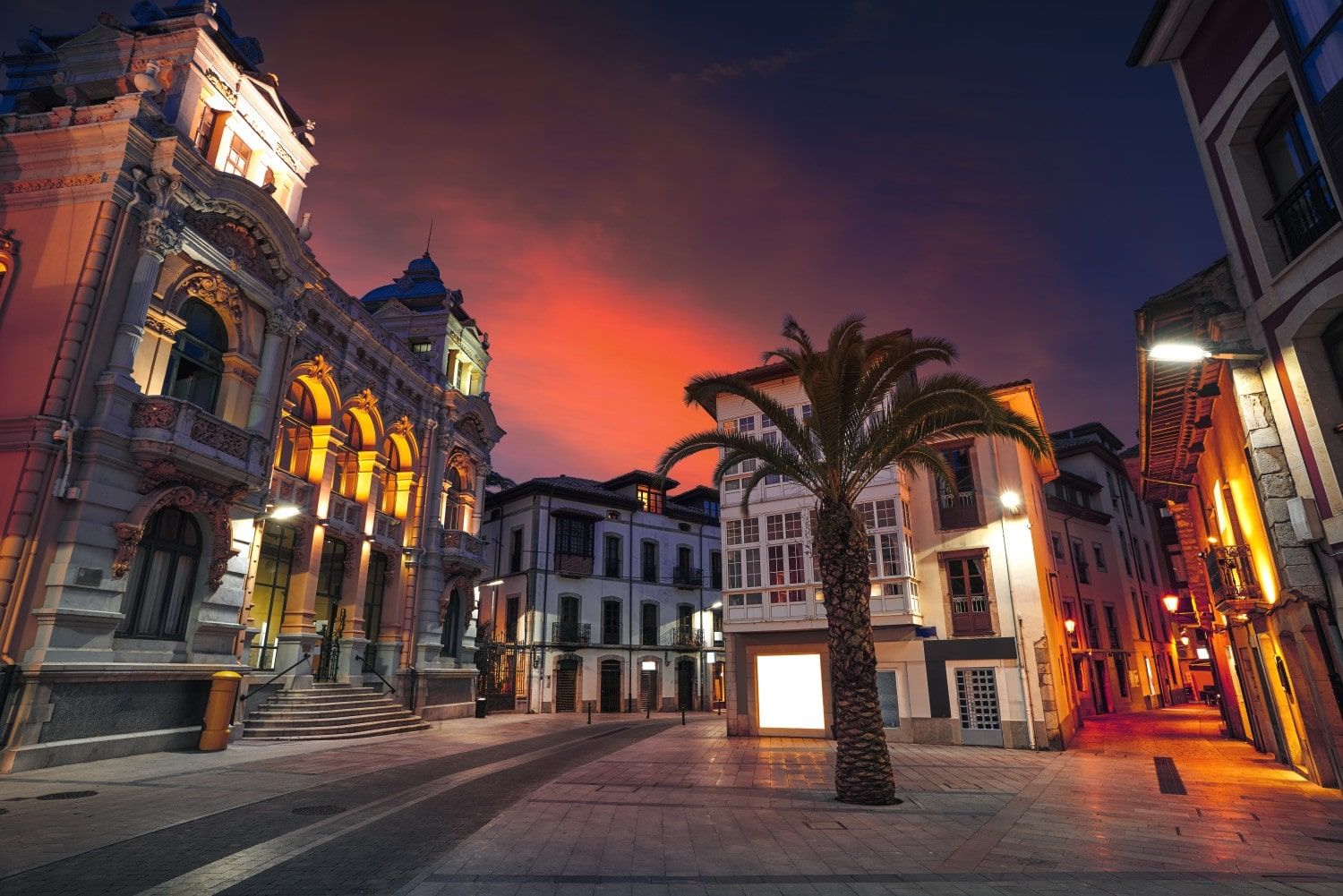 alt="Fachada iluminada del Casino de Llanes de noche, destacando su arquitectura histórica en la mágica Villa de Llanes"