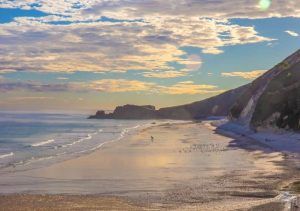 alt="Atardecer en la Playa de San Antolín, con vistas a los acantilados y el mar Cantábrico.