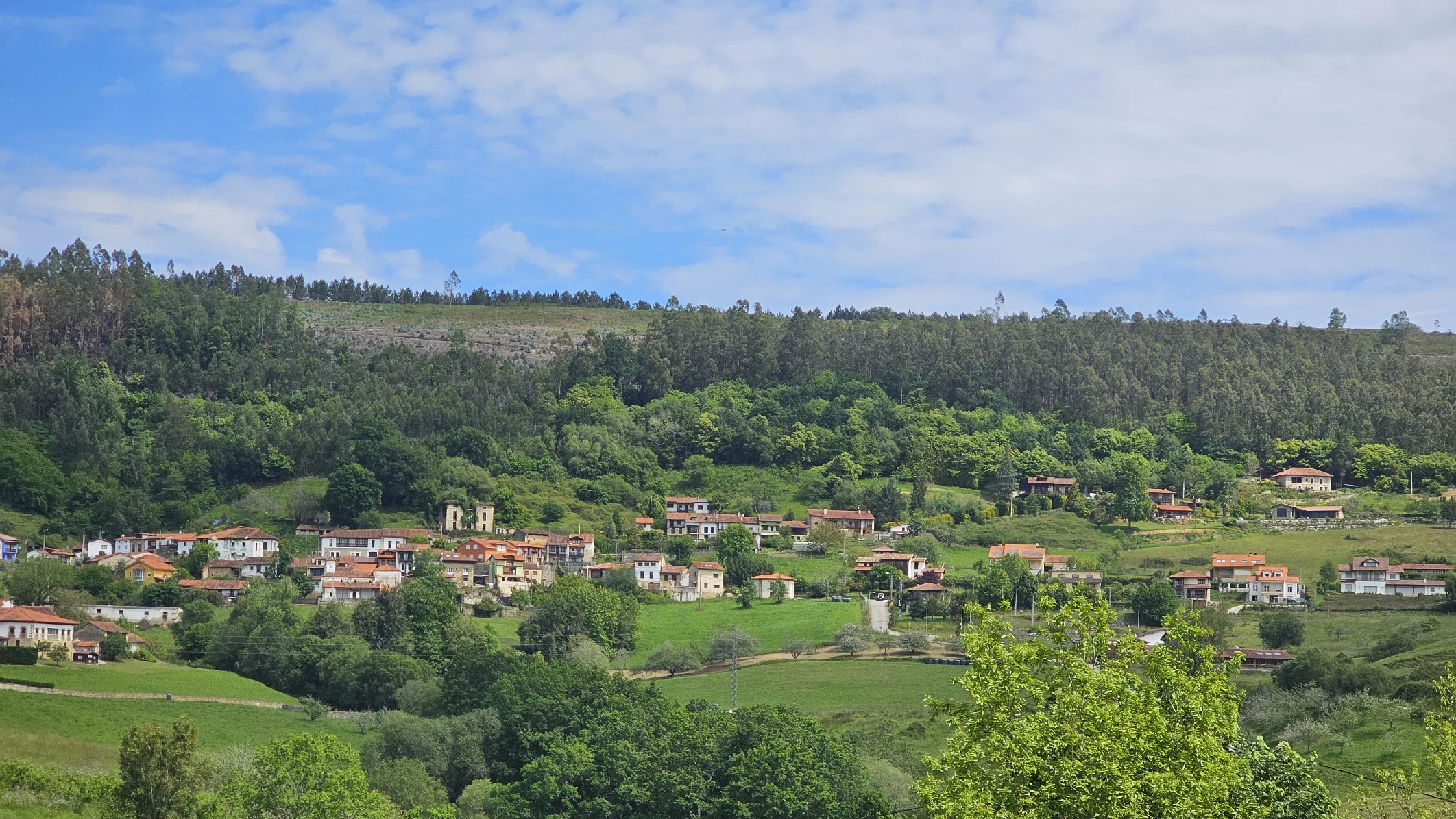 alt="Vista de Tresgrandas, un pintoresco pueblo en el concejo de Llanes, Asturias, rodeado de montañas y naturaleza exuberante."